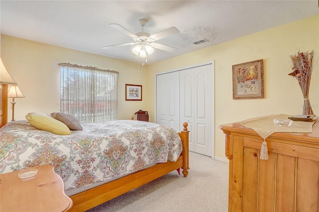 bedroom with a closet, visible vents, light colored carpet, and a ceiling fan