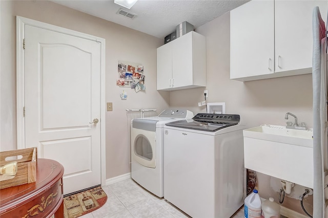 washroom featuring visible vents, a sink, cabinet space, light tile patterned floors, and washing machine and clothes dryer