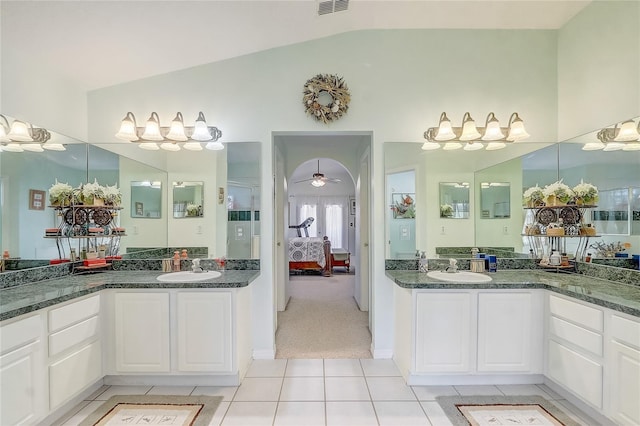 ensuite bathroom with lofted ceiling, two vanities, tile patterned floors, ensuite bath, and a sink