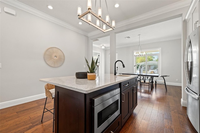 445 29th Ave N, Saint Petersburg, FL 33704 - kitchen with appliances with stainless steel finishes, a sink, a chandelier, a breakfast bar, and baseboards