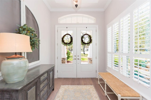 entryway featuring french doors, crown molding, and light wood finished floors