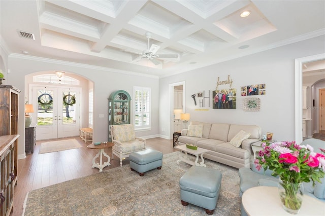 living room featuring beamed ceiling, coffered ceiling, hardwood / wood-style floors, arched walkways, and crown molding