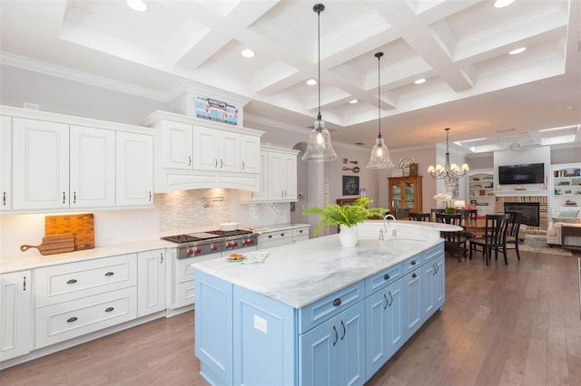 kitchen featuring wood finished floors, white cabinets, stainless steel gas stovetop, blue cabinets, and open floor plan