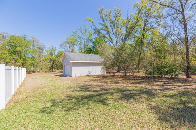 view of yard featuring an outbuilding, a garage, and fence