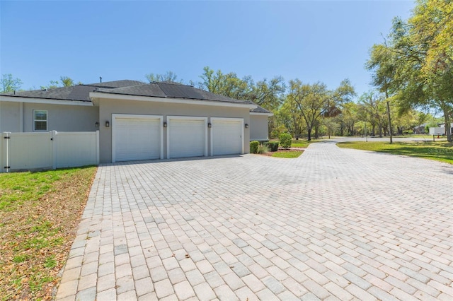 garage featuring a gate, decorative driveway, and fence