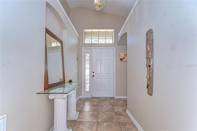 foyer featuring light tile patterned floors, arched walkways, baseboards, and high vaulted ceiling