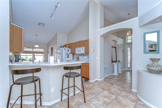 kitchen with white appliances, a breakfast bar area, light countertops, and visible vents