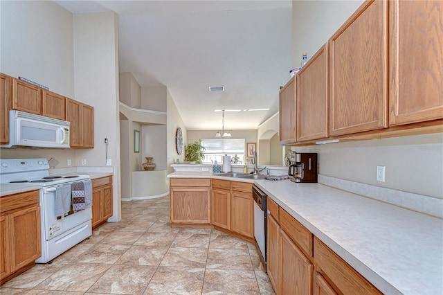 kitchen featuring visible vents, light countertops, a peninsula, white appliances, and a sink