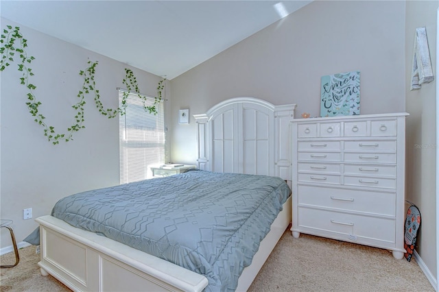 bedroom featuring lofted ceiling, baseboards, and light carpet