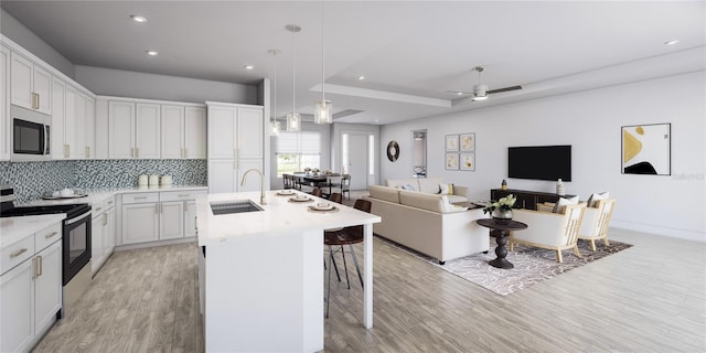 kitchen with light wood-style flooring, a sink, stainless steel microwave, tasteful backsplash, and electric range oven