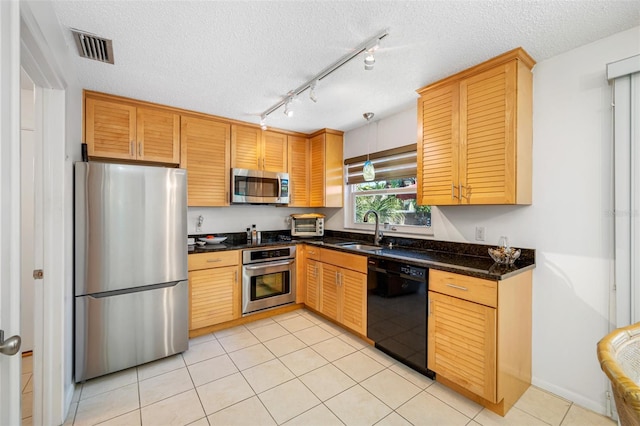 kitchen featuring visible vents, a sink, a textured ceiling, stainless steel appliances, and light tile patterned floors