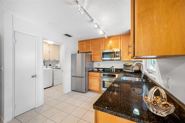 kitchen with independent washer and dryer, a textured ceiling, stainless steel appliances, and a sink