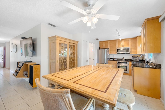 kitchen featuring visible vents, dark countertops, stainless steel appliances, light tile patterned flooring, and ceiling fan