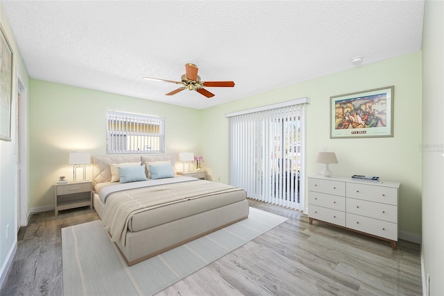 bedroom with access to exterior, a textured ceiling, wood finished floors, baseboards, and ceiling fan