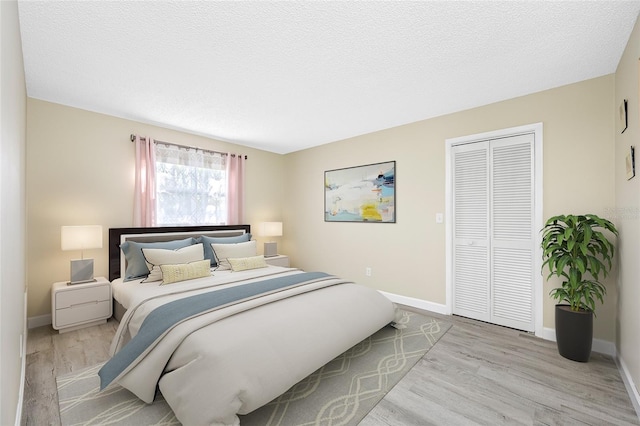 bedroom with baseboards, a closet, and light wood finished floors