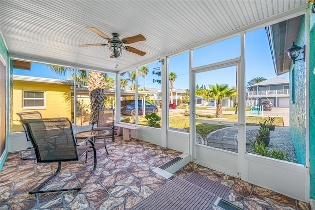 sunroom / solarium with a wealth of natural light, a residential view, and a ceiling fan