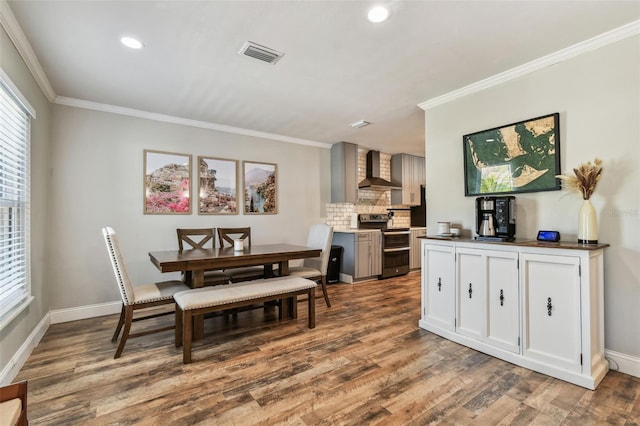 dining space featuring visible vents, crown molding, baseboards, and wood finished floors