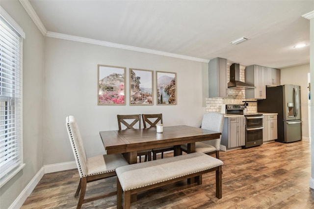 dining area with visible vents, ornamental molding, baseboards, and wood finished floors