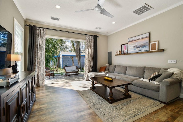 living area featuring visible vents, crown molding, and wood finished floors