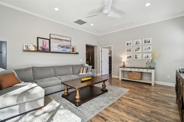 living area featuring visible vents, baseboards, attic access, ornamental molding, and wood finished floors