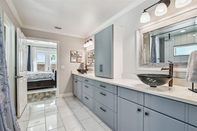 ensuite bathroom with visible vents, connected bathroom, crown molding, double vanity, and a sink