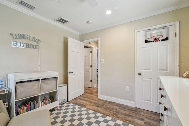 interior space with visible vents, wood finished floors, baseboards, and ornamental molding