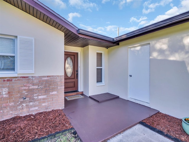 property entrance featuring stucco siding and brick siding