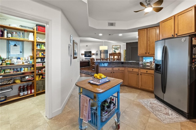 kitchen featuring visible vents, stainless steel refrigerator with ice dispenser, dark countertops, a peninsula, and brown cabinetry