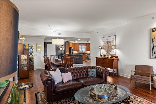 living area with dark wood-style floors, visible vents, crown molding, and baseboards