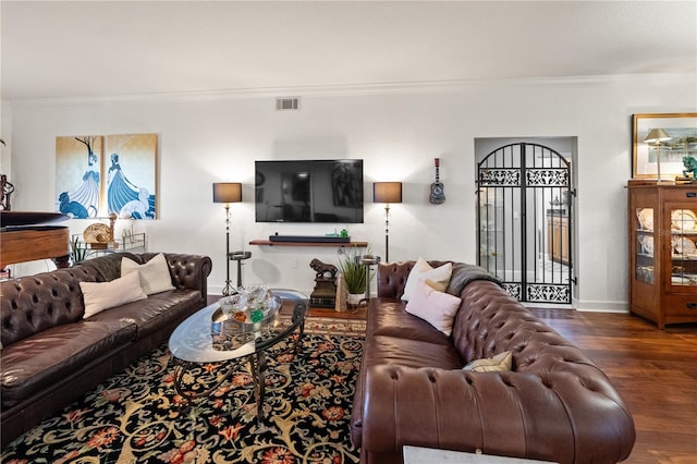 living room with visible vents, ornamental molding, baseboards, and wood finished floors