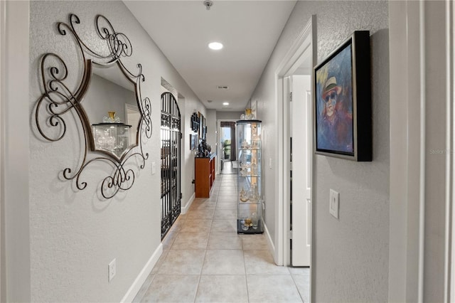 hallway with light tile patterned floors and baseboards