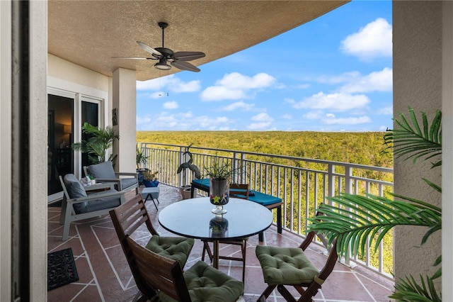 balcony with a wooded view and ceiling fan