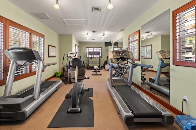 exercise room with attic access, baseboards, and visible vents