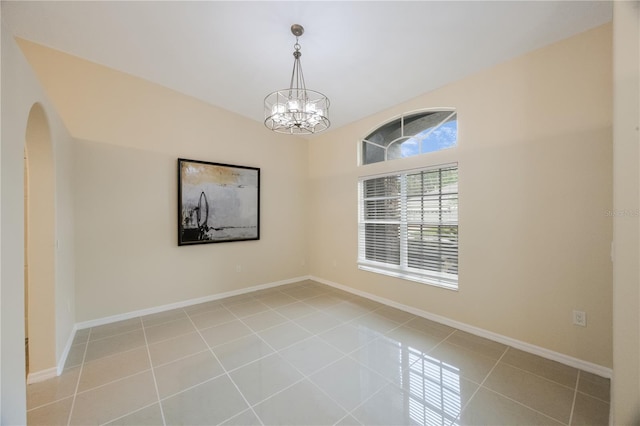 spare room featuring light tile patterned floors, baseboards, arched walkways, and an inviting chandelier