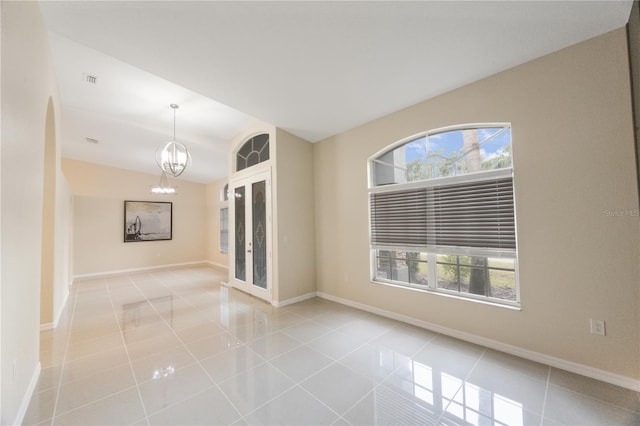 tiled spare room with baseboards, plenty of natural light, lofted ceiling, and an inviting chandelier