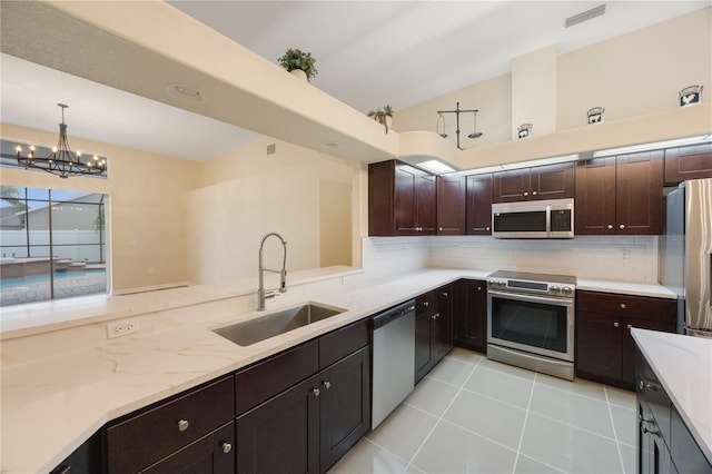 kitchen featuring a sink, light stone counters, tasteful backsplash, appliances with stainless steel finishes, and light tile patterned floors