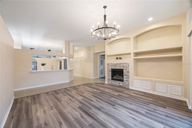 unfurnished living room featuring built in features, a fireplace, baseboards, and wood finished floors