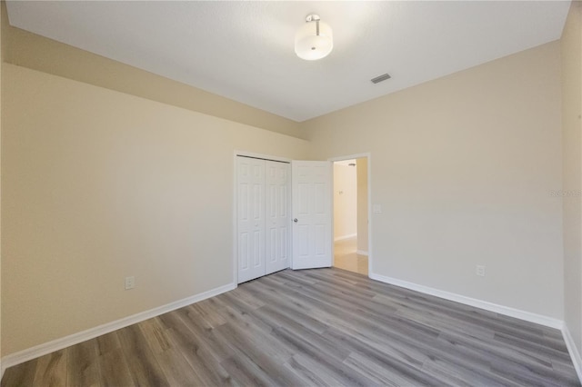 unfurnished bedroom featuring wood finished floors, visible vents, and baseboards