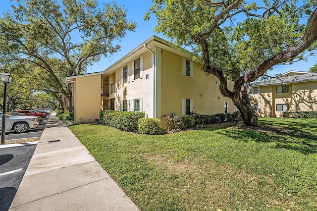 view of home's exterior featuring stucco siding, a yard, and a balcony