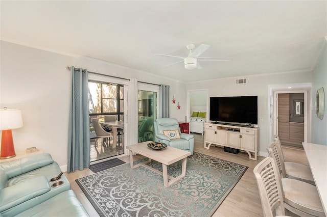 living area featuring crown molding, visible vents, light wood finished floors, and ceiling fan