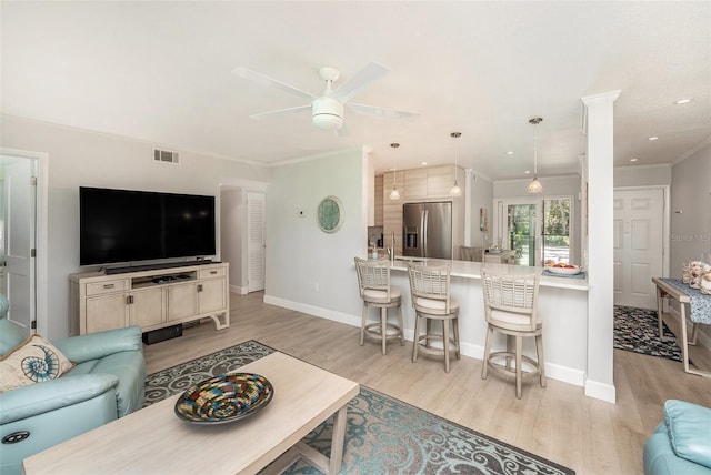 living room with visible vents, ornamental molding, a ceiling fan, light wood finished floors, and baseboards