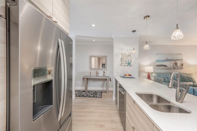 kitchen with a sink, stainless steel appliances, crown molding, and light countertops