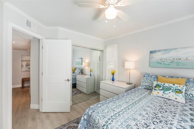 bedroom featuring ceiling fan, baseboards, ornamental molding, light wood-style flooring, and a closet