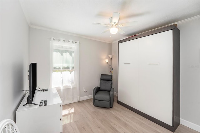 sitting room with ceiling fan, baseboards, light wood finished floors, and ornamental molding