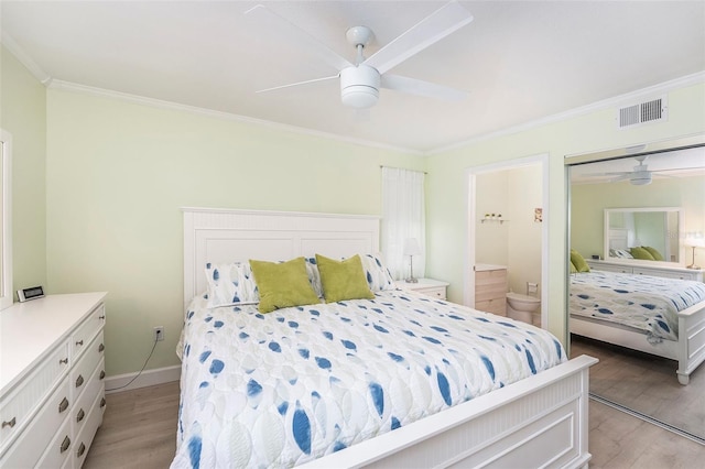 bedroom featuring visible vents, light wood-style flooring, crown molding, and connected bathroom