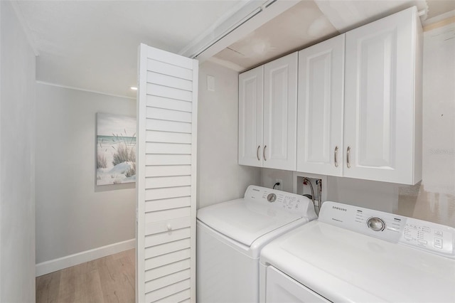 laundry area with cabinet space, light wood-type flooring, baseboards, and separate washer and dryer