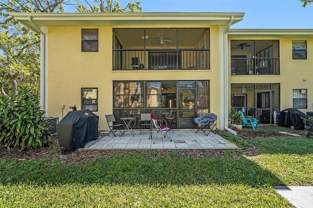 back of house featuring a sunroom, ceiling fan, stucco siding, a patio area, and a lawn