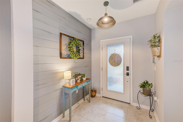 foyer entrance featuring light tile patterned flooring, baseboards, and wood walls