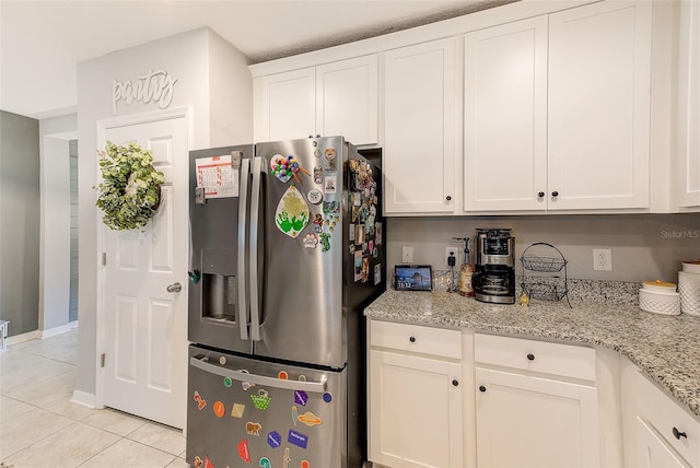 kitchen with white cabinets, light tile patterned floors, stainless steel refrigerator with ice dispenser, and light stone counters