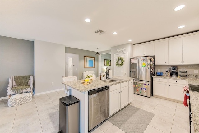 kitchen with a sink, stainless steel appliances, a kitchen island with sink, and white cabinets